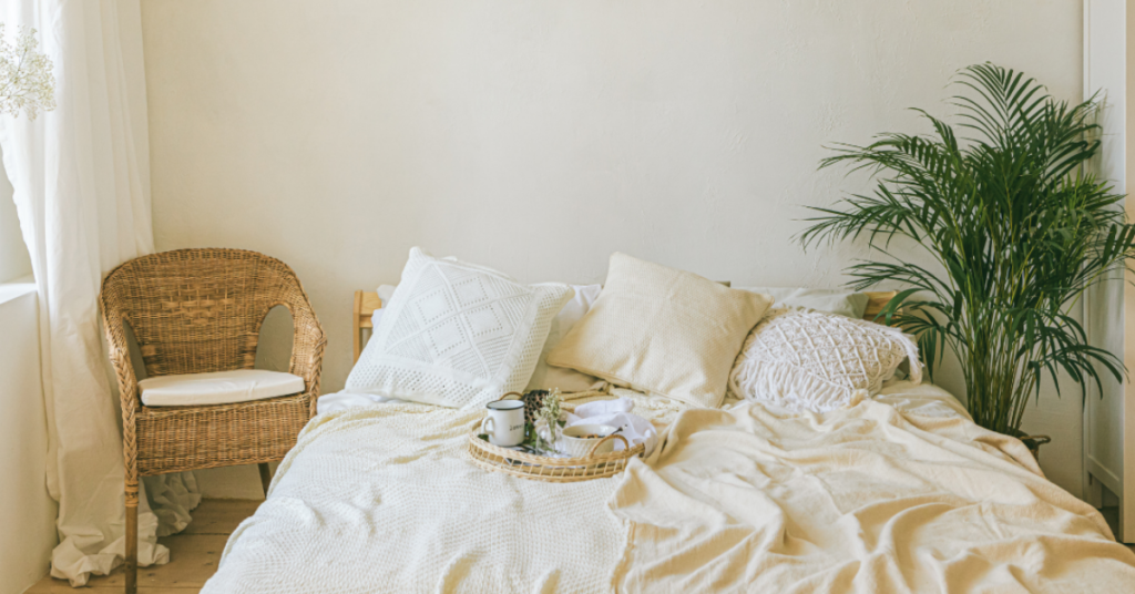 Cozy bedroom with cream sheets, plants and wicker chair