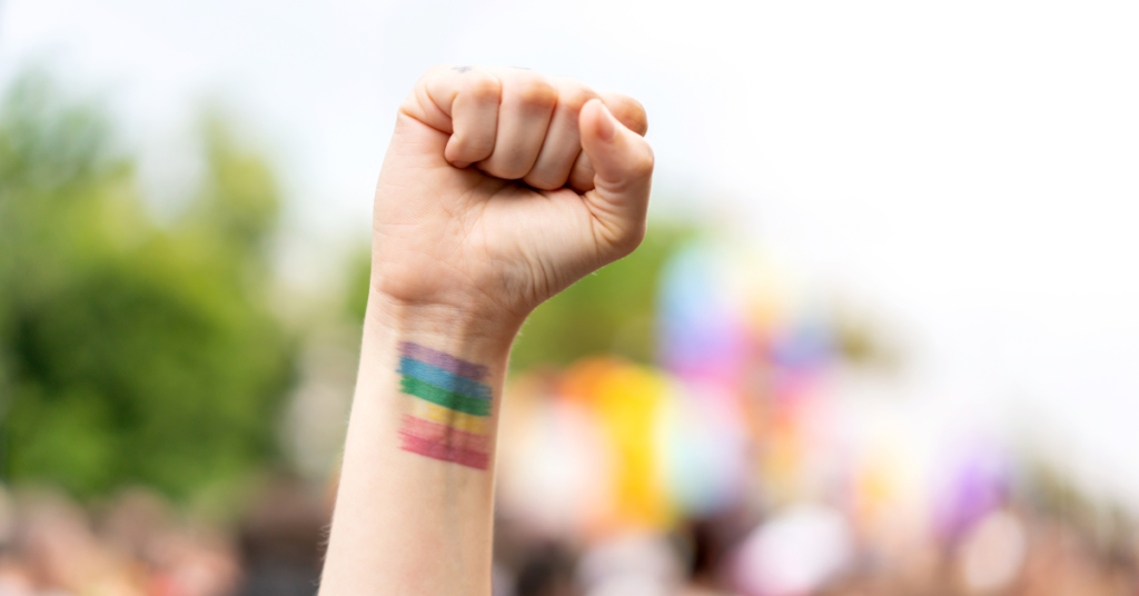 A fist in the air with rainbow painted on wrist