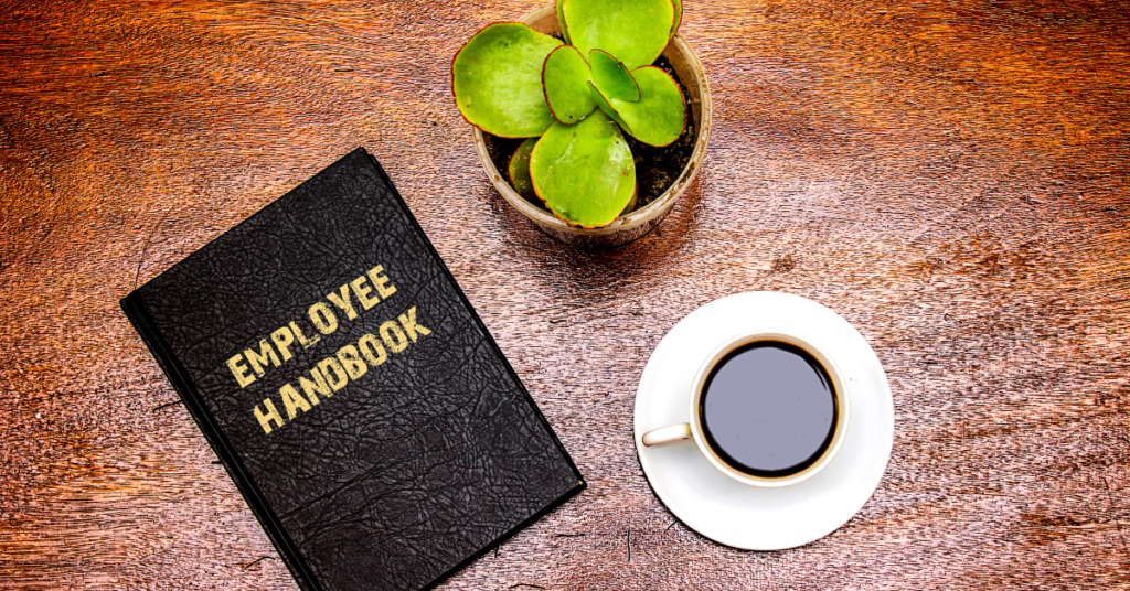 Employee handbook on a table with a plant and black coffee