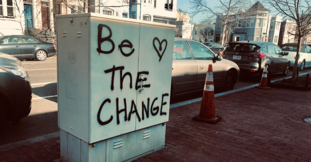 'Be the change' written in graffiti on an outdoor electrical box.