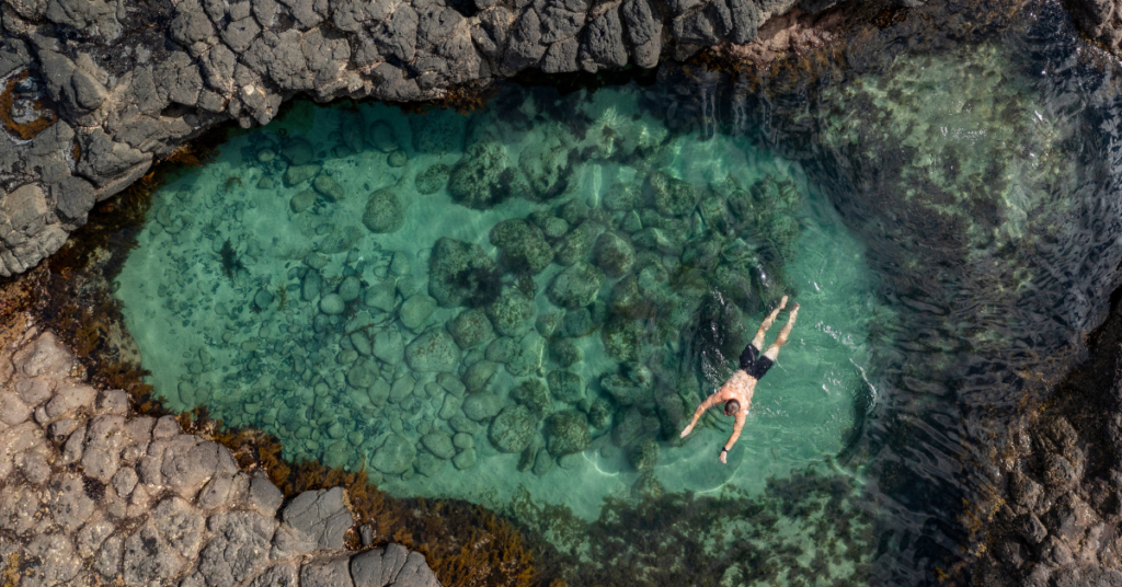 Aerial shot of person swimming in a rock pool
