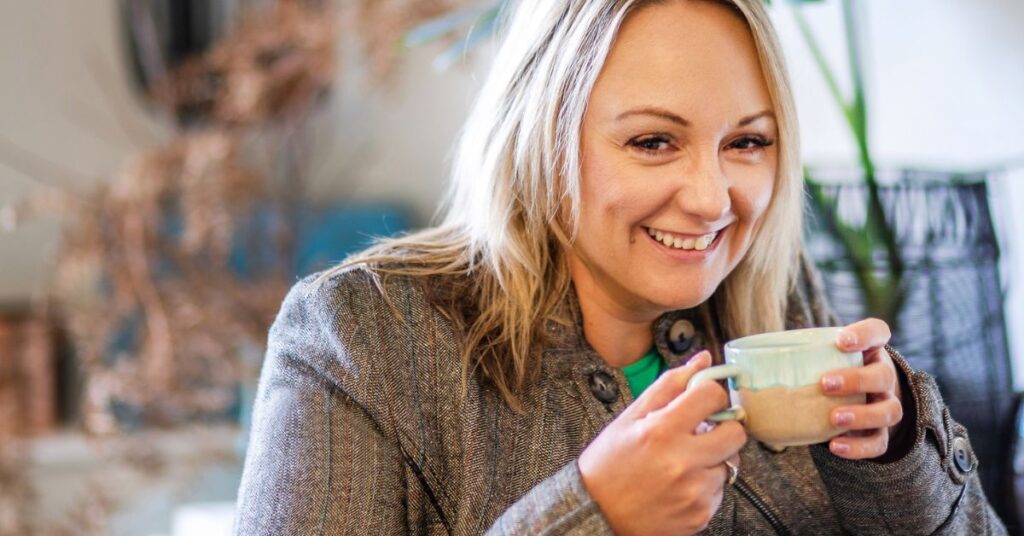 A woman holding a cup of tea and smiling