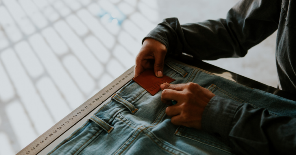 Person working on a pair of Outland Denim jeans