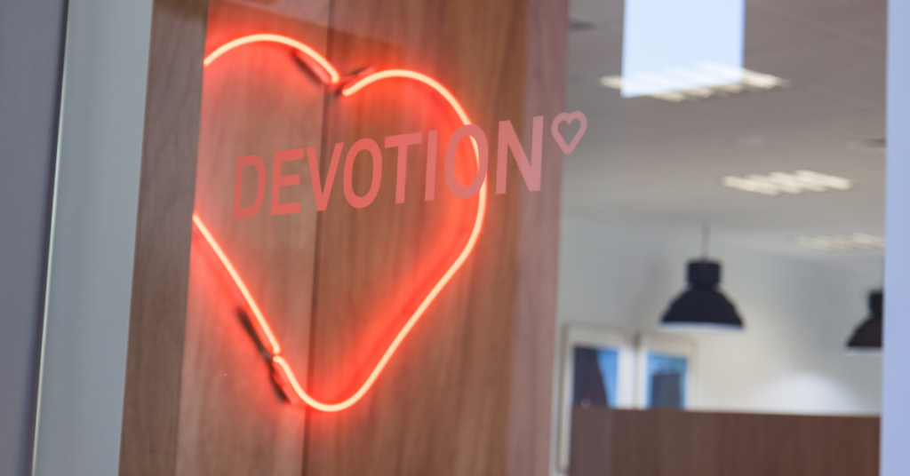 Devotion Digital logo with neon red heart in the background
