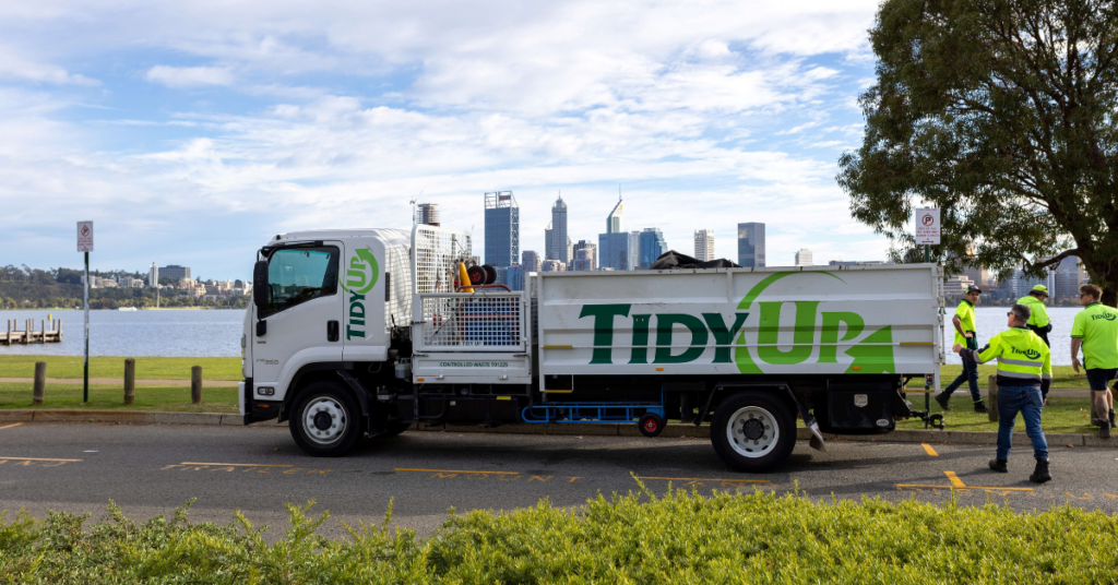 Tidy Up truck parked on the side of the road with a city in the background