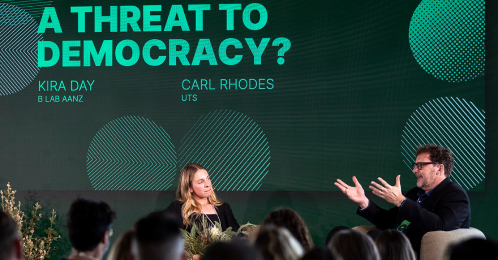 Carl Rhodes on stage talking on the topic 'Is woke capitalism a threat to democracy?'.