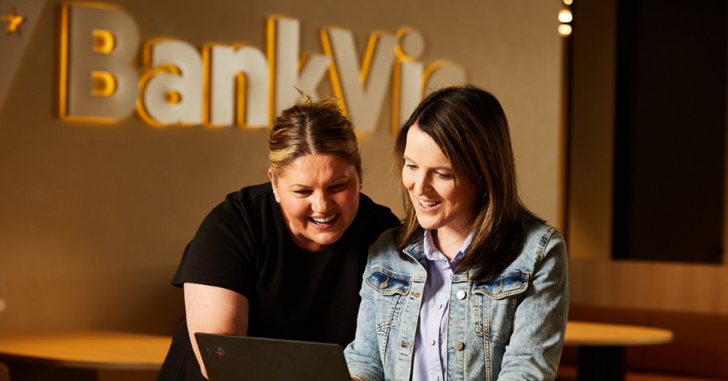 Two women employees at BankVic looking at a laptop screen and smiling