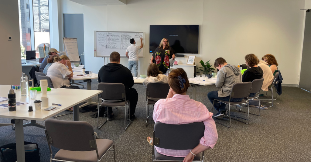 A group of people sitting in a meeting room listening to a presenter at Guidestar Psychology.