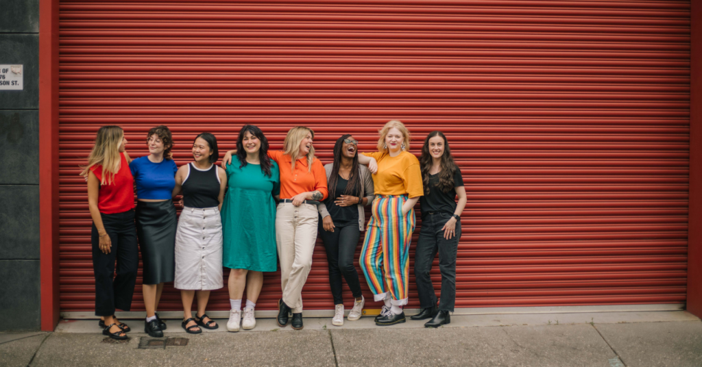 A group of women from Code Like a girl standing in front of a red shutter gate 