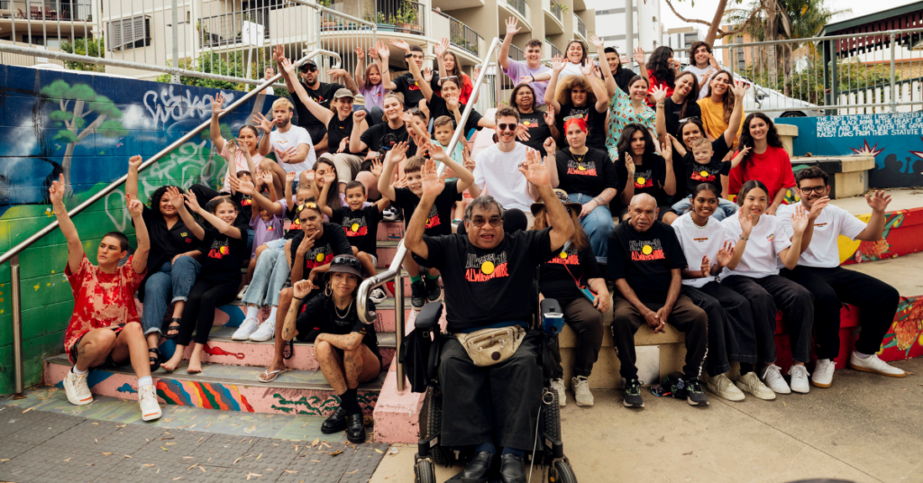 A group of people cheering and celebrating the brand Clothing The Gaps in their "Always Have, Always Will Be" printed t-shirts