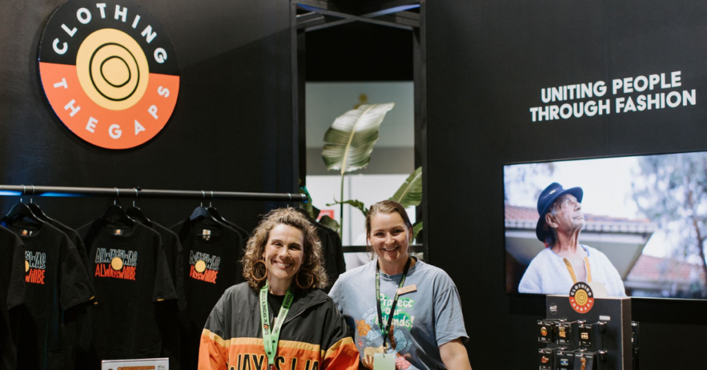 Two Clothing The Gaps staff posing in front of their B Corp Booth at SXSW Sydney 2024 wearing the brand's merch. 