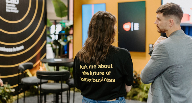 Image of a woman and a man talking to each other at The B Corp SXSW Sydney Booth.