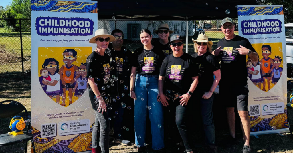 New B Corp Carbon Creative team members at a Childhood immunisation site wearing black t-shirts with the childhood immunisation logo and artwork printed on the t-shirts.