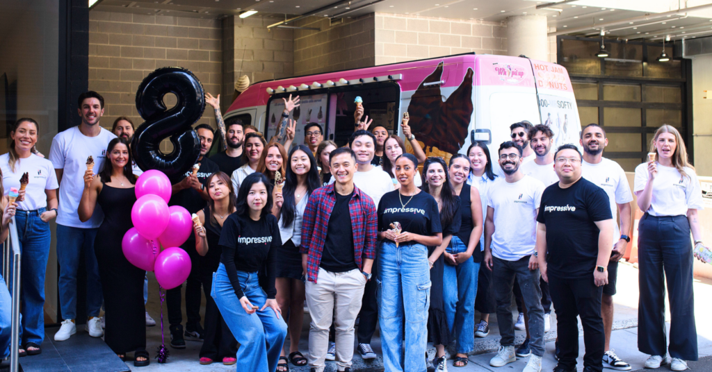 B Corp Impressive Digital's team standing and posing in front of an icecream truck with a big 8 shaped balloon at the back.