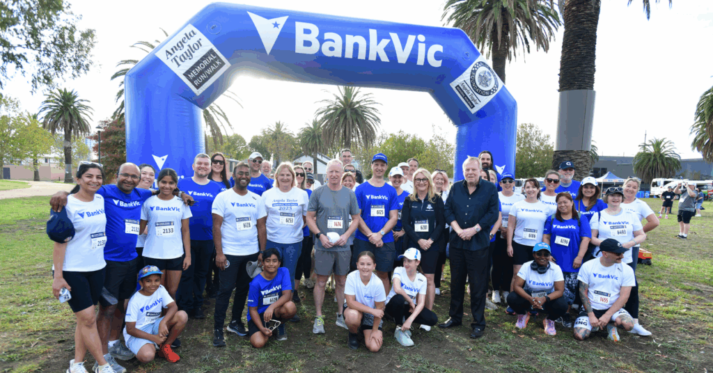 BankVic employees posing in front of a big blue float gate