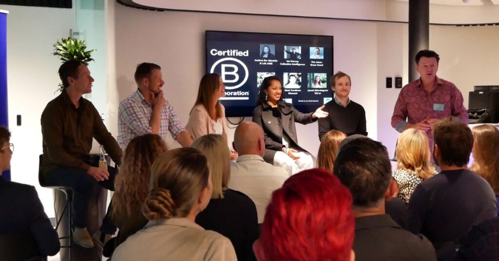 A panel of six, sitting in front of a screen 