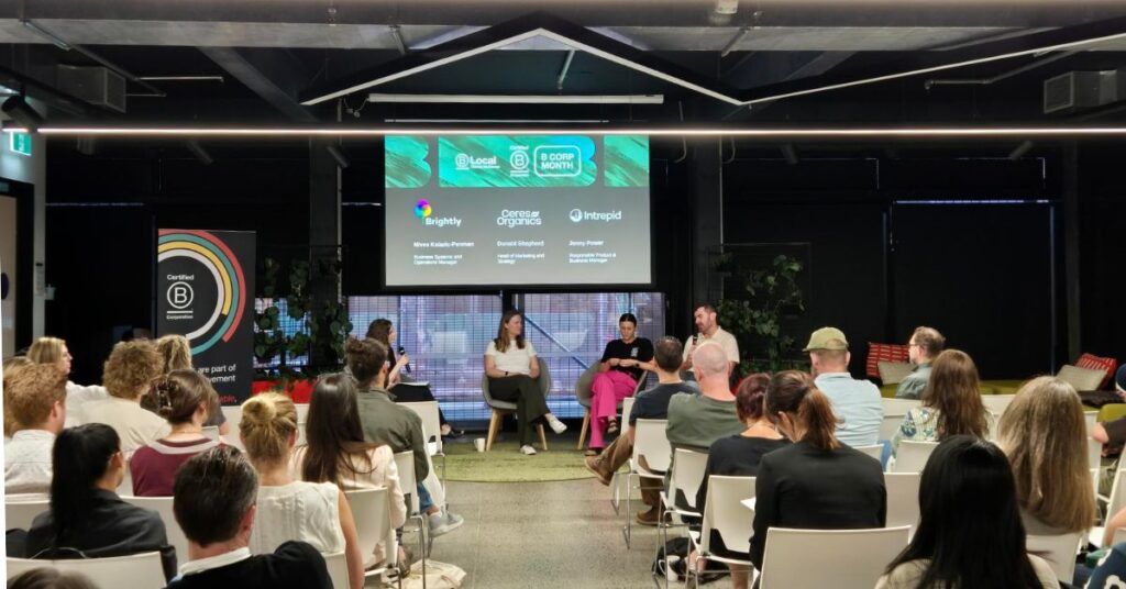 A panel of four talking in front of a room full of people