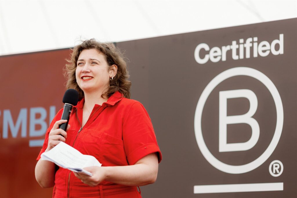 Erica McCalman in front of a B Corp sign, speaking to the audience on a microphone