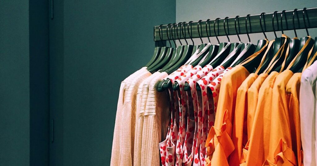 A clothes rack in a shop showing orange and pink clothes