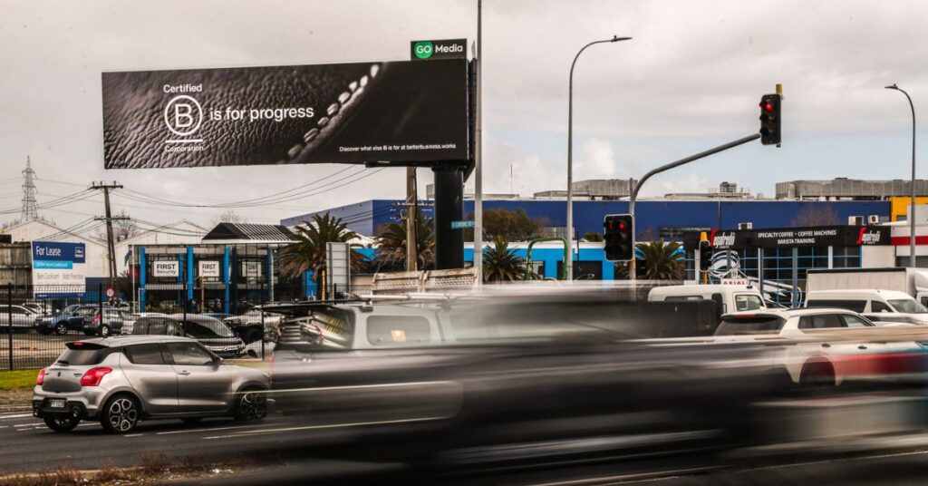 'B is for progress' billboard above a busy road