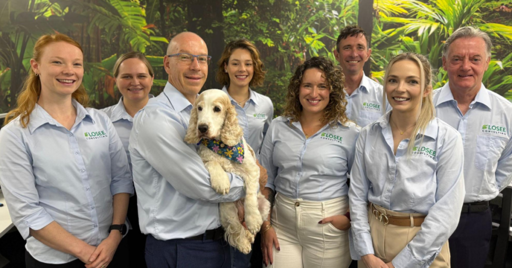 The Losee Consulting team (8 people in light blue shirts), including one dog being held.