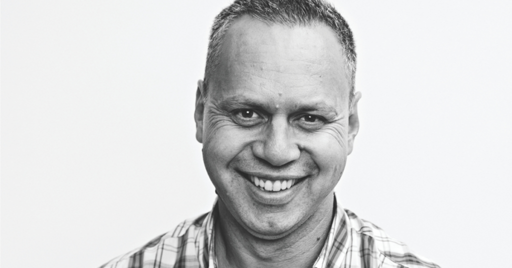 A black and white headshot of Wayne Denning.