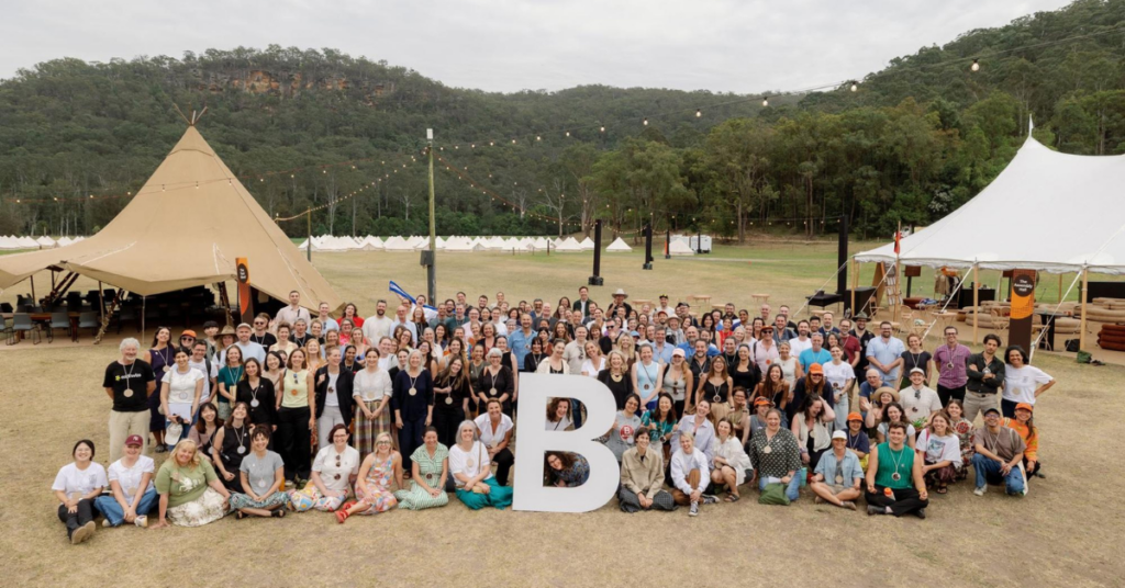 Large group photo of B Lab AANZ Assembly attendees gathered outdoors around a large B Corp “B” sign.