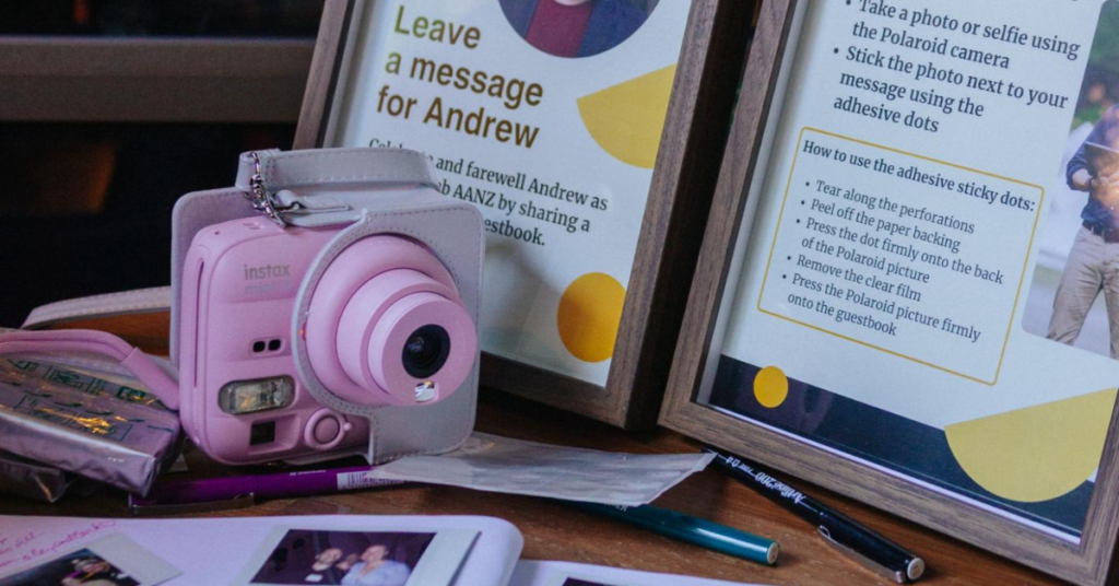 Guestbook table with an instant camera, printed instructions and handwritten farewell messages for Andrew.