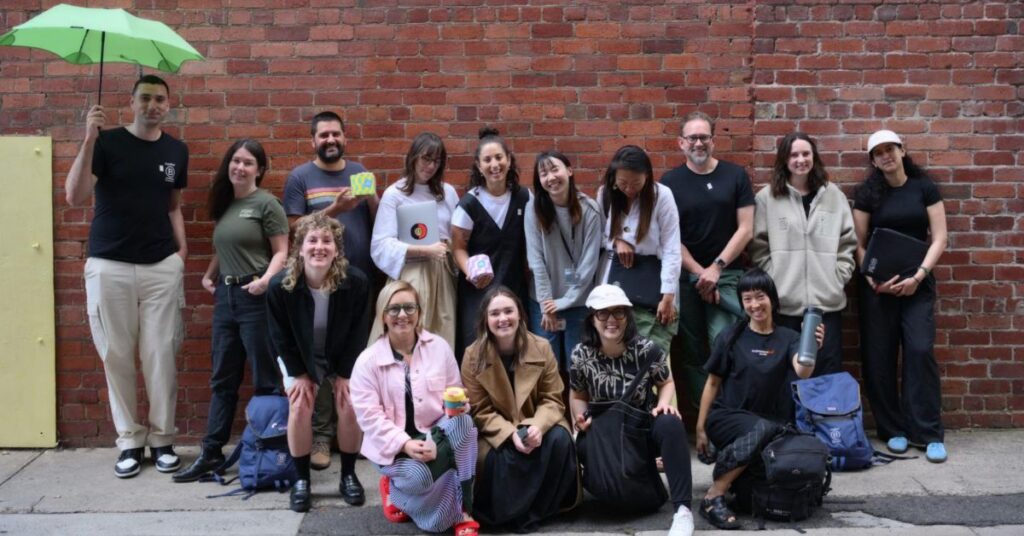 Group of B Lab AANZ team members standing together in front of a brick wall.