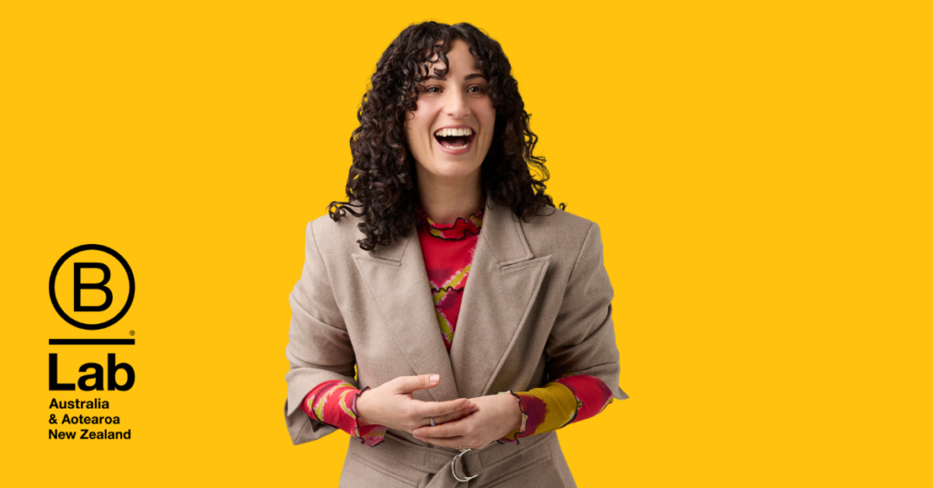 Katie Russo, Marketing Manager at B Lab AANZ, smiling in front of a block yellow background.