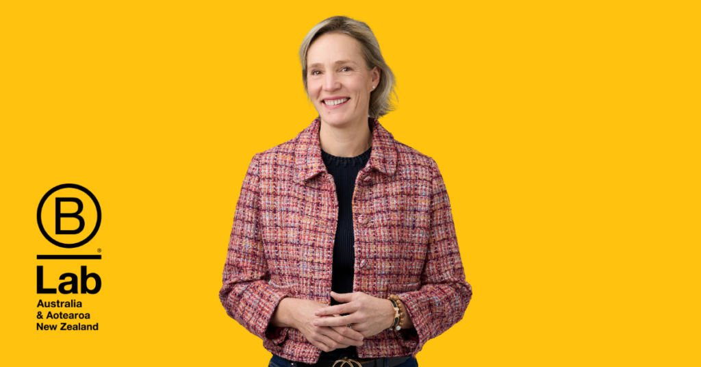 Kate Healy, Regional Director at B Lab AANZ, smiling in front of a block yellow background.