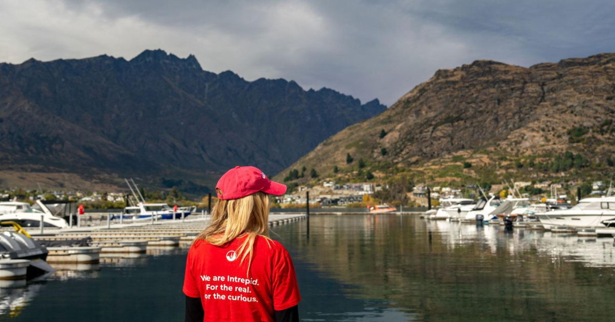 Intrepid team member overlooking a marina and mountains.
