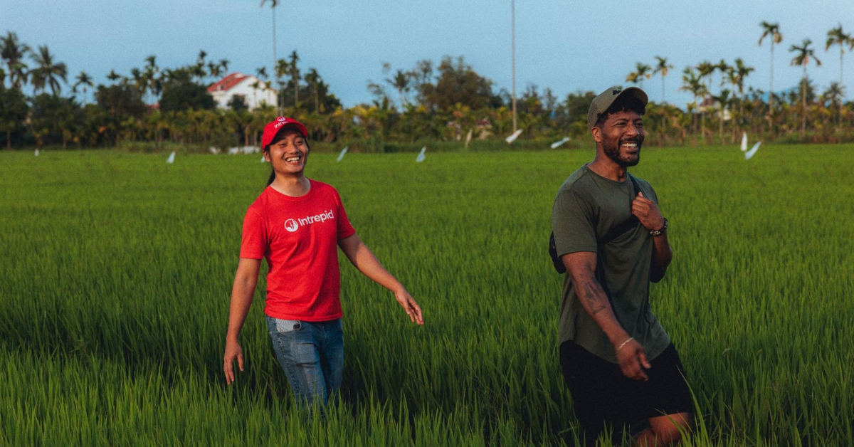 Intrepid team member walking through a green field with a traveller.